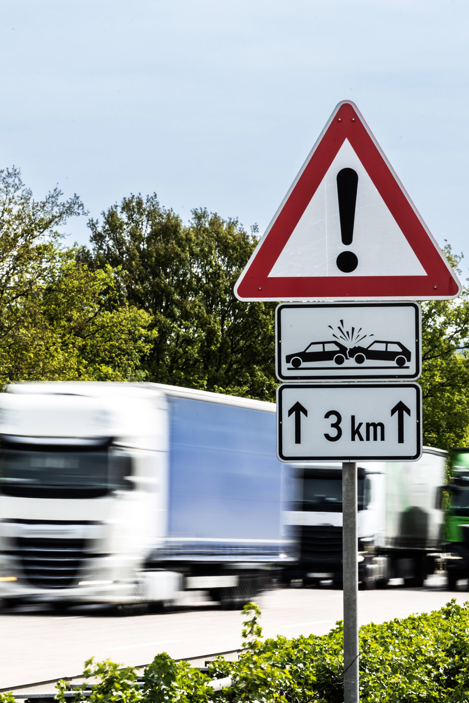 a road sign with a exclamation point and a truck in the background